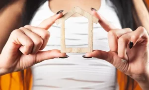 Mujer sosteniendo una casa prototipo por beneficios de la ley de vivienda de interés social en Colombia